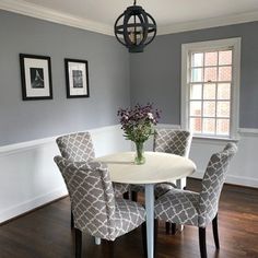 a dining room table with four chairs and a vase of flowers on top of it