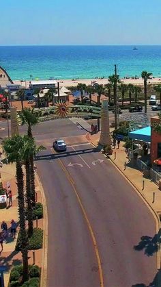 an aerial view of the beach with palm trees and people walking on the sidewalk near the ocean