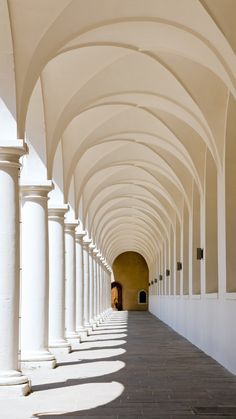 an arched walkway lined with white columns and arches