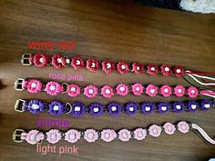 four different types of pink, purple and white flowered hair clips on a wooden table