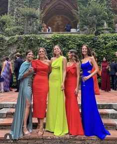 four women in colorful dresses posing for a photo on the steps at an outdoor event