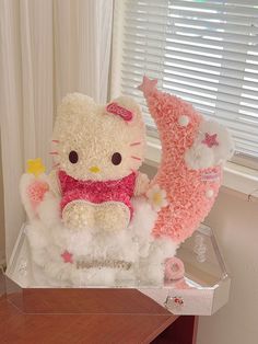 two hello kitty stuffed animals sitting on top of a wooden table next to a window