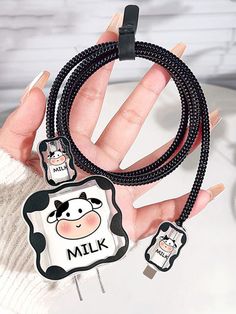 a hand holding a black and white cow charm