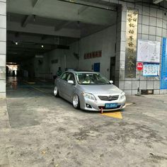 a silver car parked in an empty parking garage with chinese writing on the wall behind it