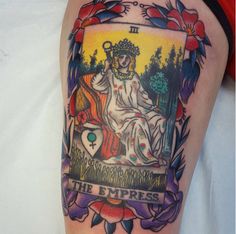 a woman with a tattoo on her arm holding a tarot card in front of her