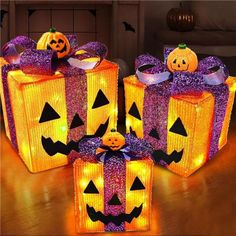 three lighted halloween gift boxes with jack - o'- lanterns and pumpkins on them