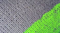 a close up view of the side of a knitted blanket with green and grey stripes