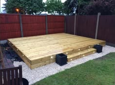 a large wooden deck in the middle of a yard with lights on it's sides