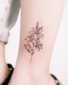 a small tattoo on the ankle of a woman's leg with flowers in it