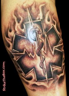 an image of a medical tattoo on someones left arm with fire and cross in the background