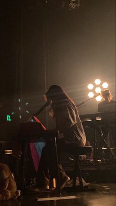 two people sitting on stools in front of a stage with lights and a dog