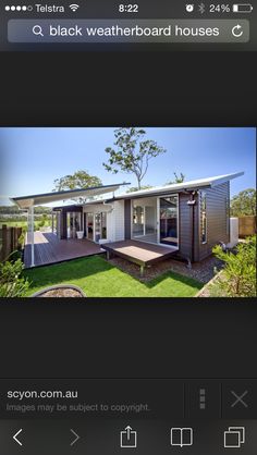 a house that is in the grass with a deck and some windows on top of it