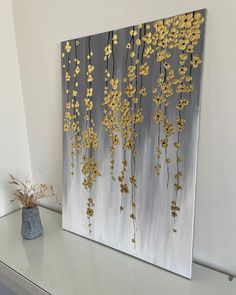 a painting with gold flowers on it sitting on a shelf next to a potted plant