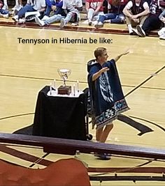 a woman standing on top of a basketball court next to a table with a trophy