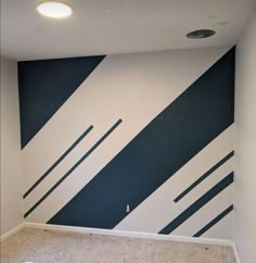 an empty room with blue and white stripes painted on the wall, carpeted floor