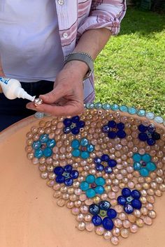 a woman is making something out of glass beads