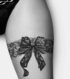 a woman's thigh with a black lace garter and a bow on it