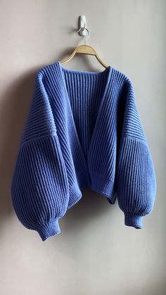 a blue sweater hanging on a wall with a hanger in front of the top