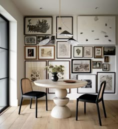 a dining room table with chairs and pictures on the wall