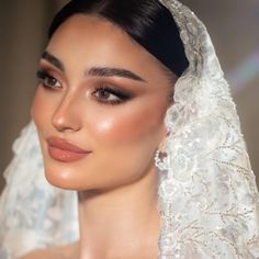 a woman wearing a veil and makeup looks into the distance while posing for a photo