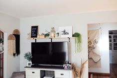 a flat screen tv sitting on top of a white entertainment center in a living room