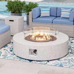 a fire pit sitting on top of a patio next to a blue couch and table