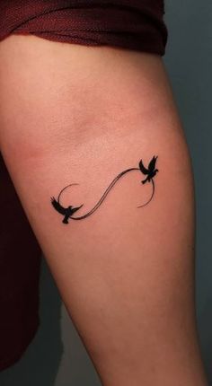 a woman's arm with two birds on it and one bird flying in the air