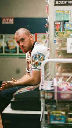 a man sitting on top of a counter in a store