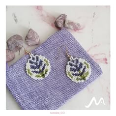 a pair of earrings sitting on top of a purple cloth next to rocks and stones