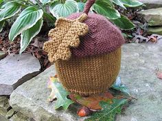 a knitted cupcake hat sitting on top of a rock next to some leaves