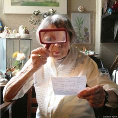 an older woman sitting in a chair looking through a magnifying glass at something