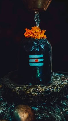 a black vase with orange flowers on it and water pouring from the top, in front of a dark background