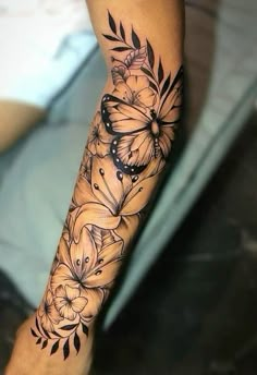 a woman's leg with flowers and butterflies tattoo on her arm, which is black and white