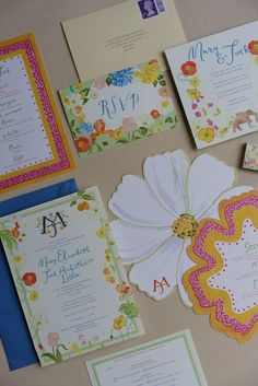 the wedding stationery is laid out neatly on the table with flowers and other items