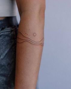 a woman's arm with a tattoo on it that has waves and dots in the middle