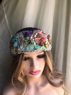 a mannequin head wearing a hat with flowers and pearls on it's side