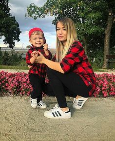 a woman kneeling down next to a little boy in black and red flannel