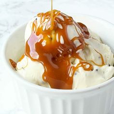 an ice cream sundae with caramel drizzled on top in a white bowl