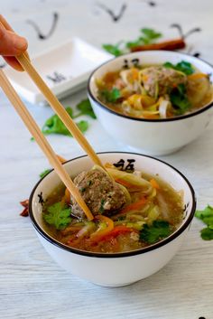 two bowls of soup with chopsticks in them