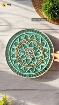 a green plate sitting on top of a wooden table next to a potted plant