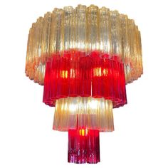 a red and yellow glass chandelier hanging from the ceiling in front of a white background