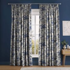 a living room with blue walls and curtains on the window sill, in front of a