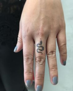 a woman's hand with a small tattoo on her left ring and the other finger