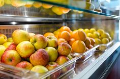 apples, oranges and lemons are on display in plastic containers at a grocery store