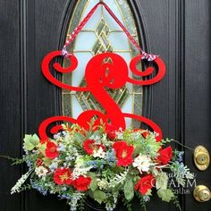 a black front door with a red and white wreath hanging on it's side