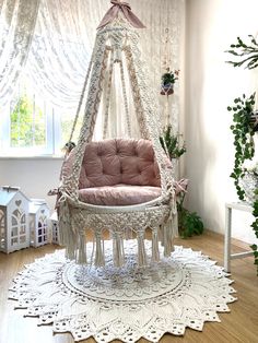 a pink chair sitting on top of a wooden floor next to a white rug and window