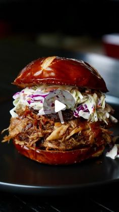 a pulled pork sandwich with coleslaw and slaw on a black platter