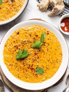 two bowls of soup on a table with bread