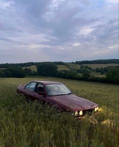 a car that is sitting in the middle of some tall grass with its headlight on