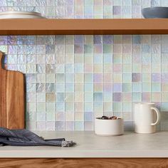 a wooden cutting board sitting on top of a counter next to cups and saucers